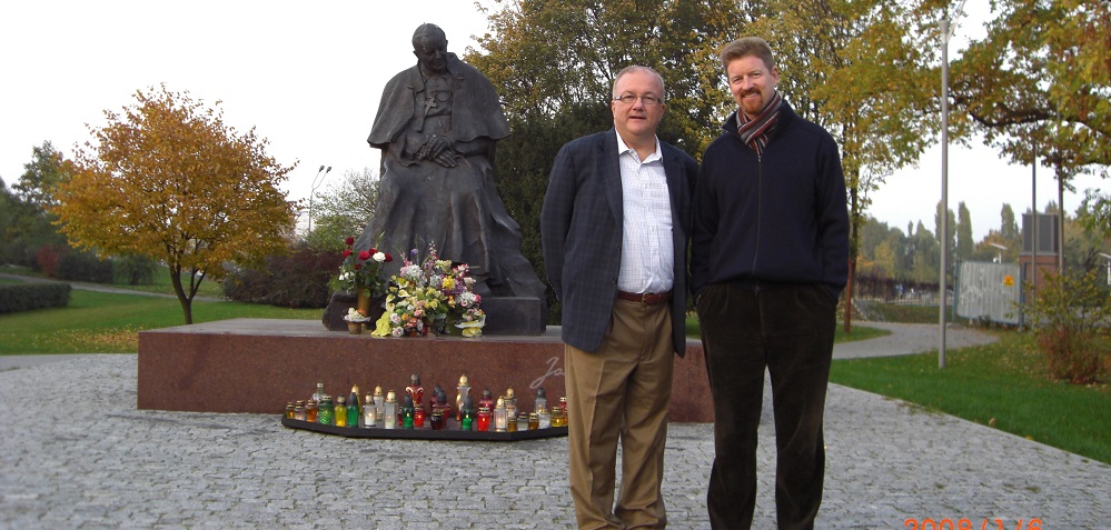 John Kurowski and current Director Todd Waller in front of a statue of John Paul II 
